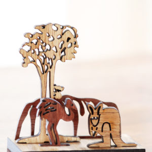 A wooden mini landscape of an Australian image with Uluru, a kangaroo, an emu and a koala in a gum tree. Four wooden images sit into a wooden base to make up the 3D landscape.
